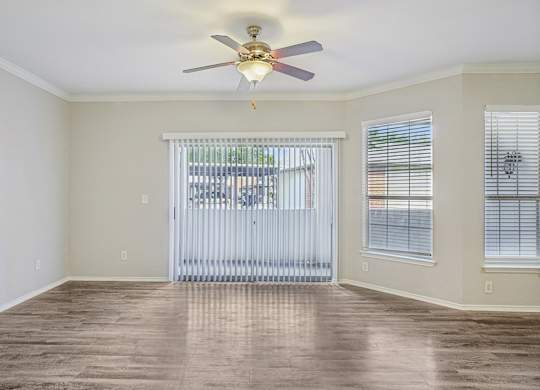 A room with a ceiling fan and sliding glass doors.