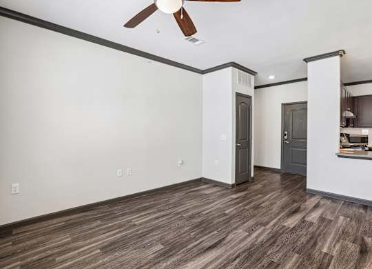 A room with a ceiling fan and wood flooring.