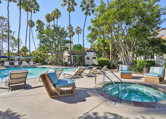 A pool area with a hot tub and lounge chairs.