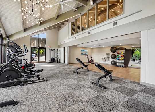 A gym with a variety of equipment including treadmills, weights, and exercise machines.