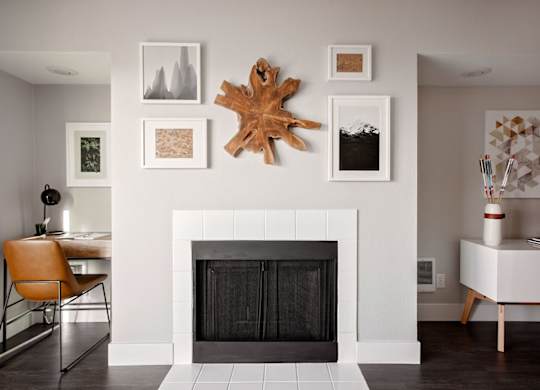 A fireplace with a leaf decoration above it and pictures on the wall.