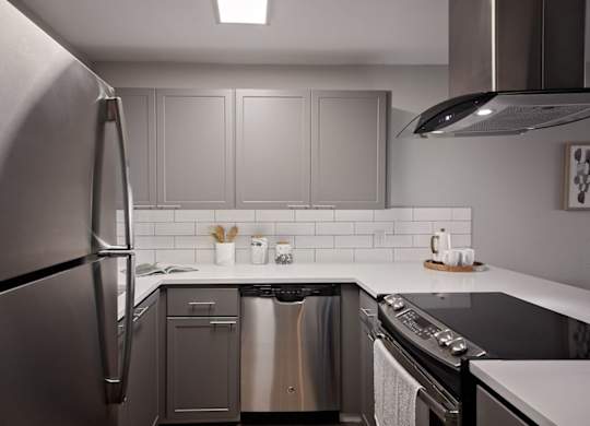 Apartments for Rent in Mountain Park - MiLO at Mountain Park - Chef-Grade Kitchen, with White Countertops and Backsplash, Grey Cabinetry, Black Electric Stovetop, and a Refrigerator.