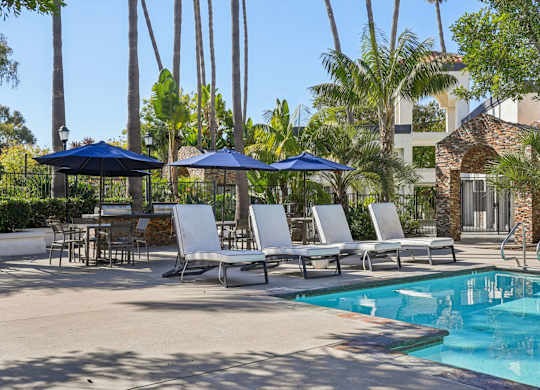 A pool area with chairs and umbrellas.