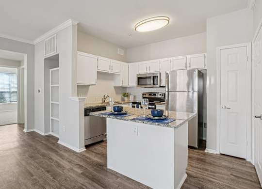 A kitchen with white cabinets and a wooden floor.