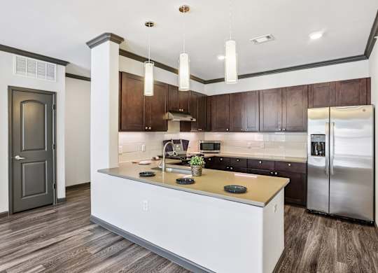 A modern kitchen with a white island and dark wood cabinets.