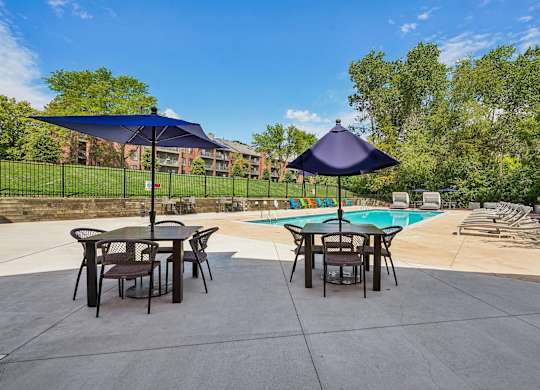 A patio with a table and chairs and a pool in the background.