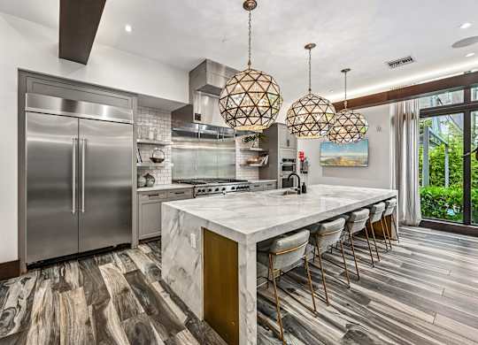 A modern kitchen with a marble countertop and stainless steel appliances.