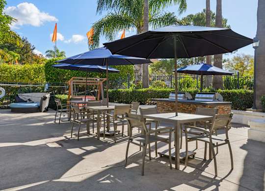 A patio with tables and chairs and umbrellas.