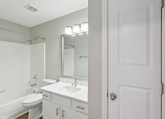 A white bathroom with a toilet, sink, and mirror.