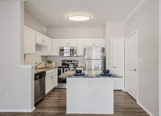 A kitchen with white cabinets and a white island.