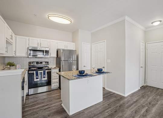 A kitchen with white cabinets and a wooden island.