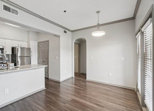 A kitchen with white cabinets and a wooden floor.