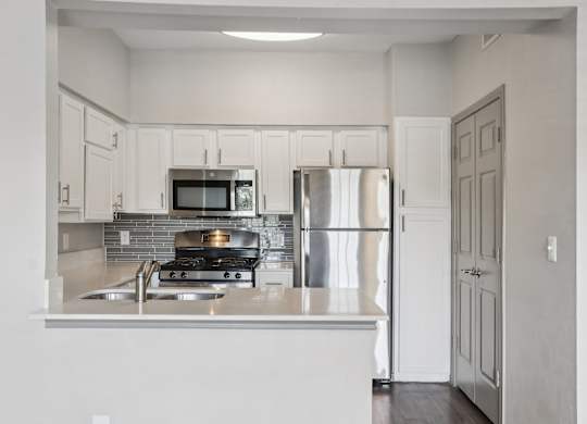 A kitchen with a stove, refrigerator, and microwave.