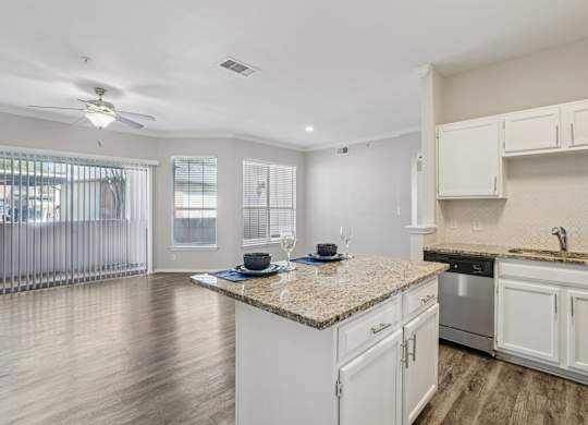 A kitchen with white cabinets and a granite countertop.