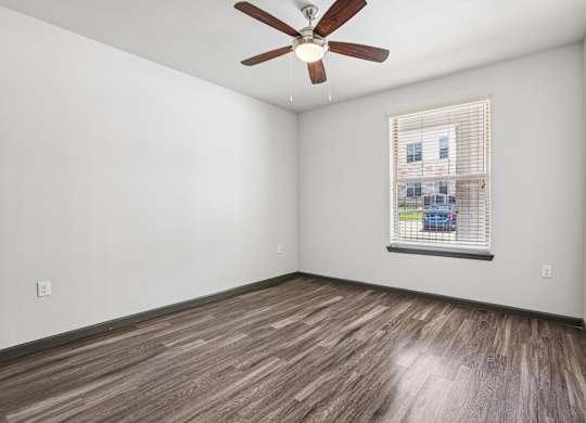 A room with a ceiling fan and a window with blinds.