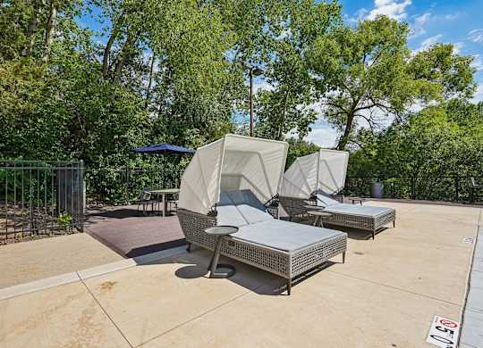 A patio area with a table and chairs covered by a white canopy.