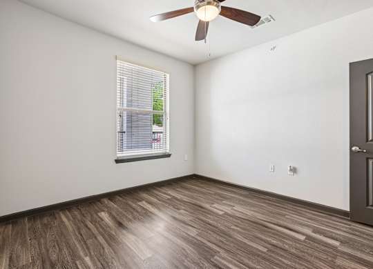 A room with a ceiling fan and a window with blinds.