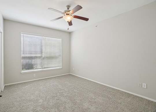A room with a ceiling fan and a window with blinds.