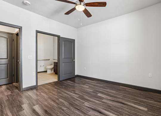 A room with a ceiling fan and wooden flooring.