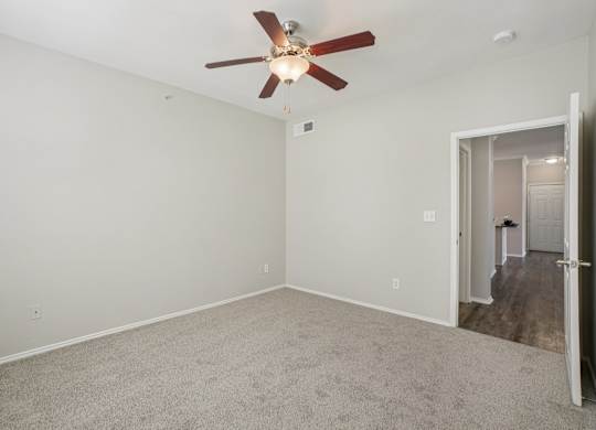 A room with a ceiling fan and carpeted floor.