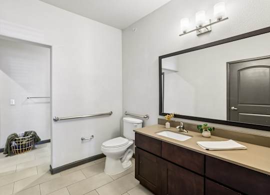 A bathroom with a toilet, sink, and mirror.
