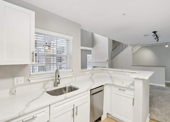 A kitchen with white cabinets and a marble countertop.