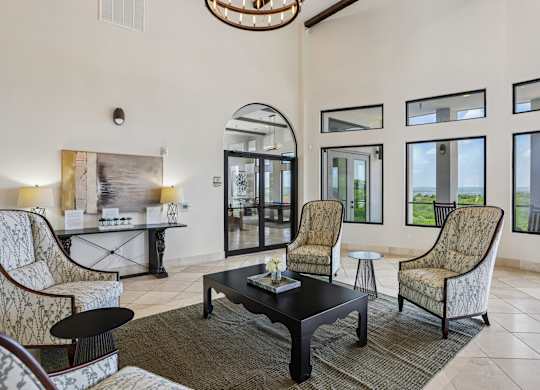 A living room with a black coffee table and patterned chairs.