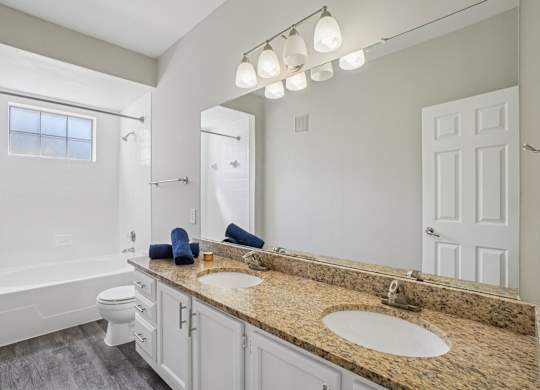 A bathroom with a granite countertop and white fixtures.