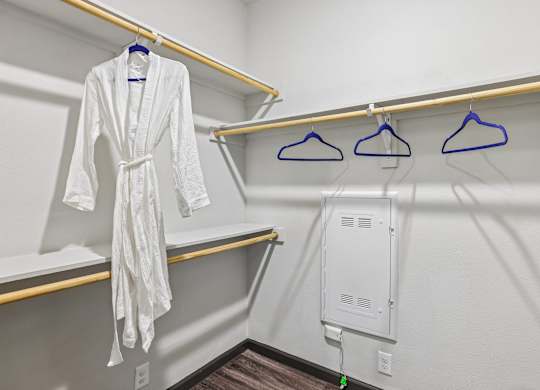 A white robe is hanging on a hanger in a room.