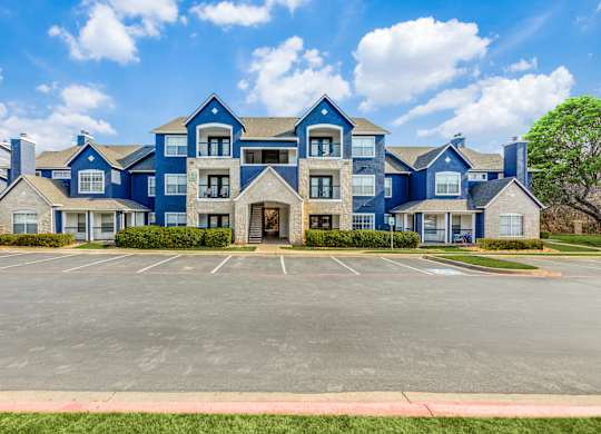 A large blue building with a parking lot in front.