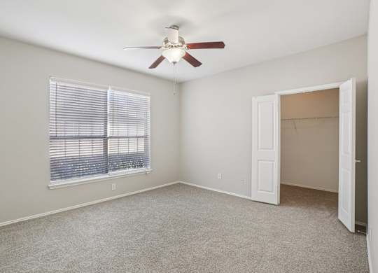 A room with a ceiling fan and a window with blinds.