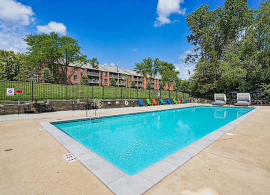A large swimming pool surrounded by trees and a building in the background.
