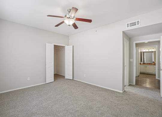 A room with a ceiling fan and carpeted floor.