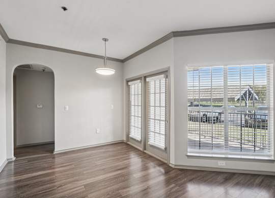 A room with a wooden floor and a large window with blinds.