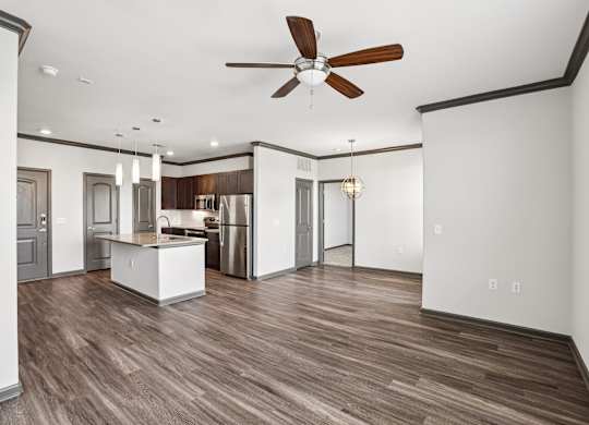 A modern kitchen with a wooden floor and a ceiling fan.