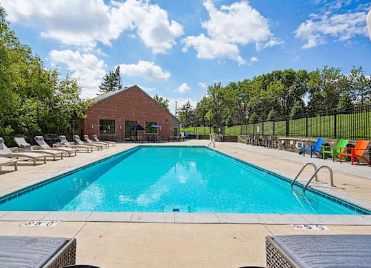 A large swimming pool surrounded by lounge chairs and trees.