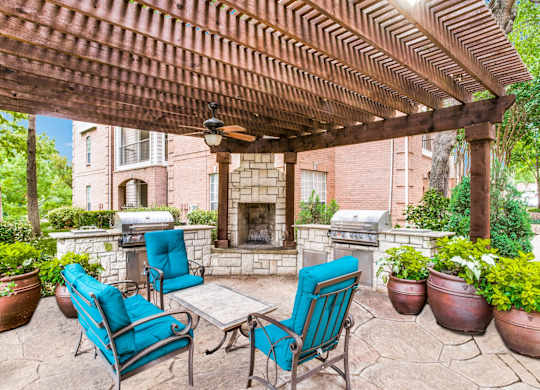Luxury Apartments in North Dallas TX- Outdoor Patio With Fireplace, Two Grills, and Comfortable Blue Outdoor Chairs
