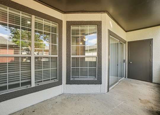 A concrete balcony with a sliding door and windows.