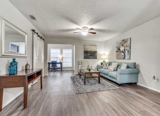 A living room with a blue couch and a wooden table.