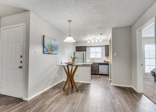A room with a white door, a table with a plant on it, and a painting on the wall.