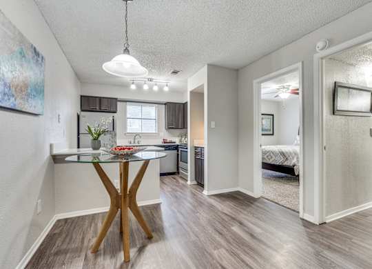 A modern kitchen with a glass table and a wooden X base.
