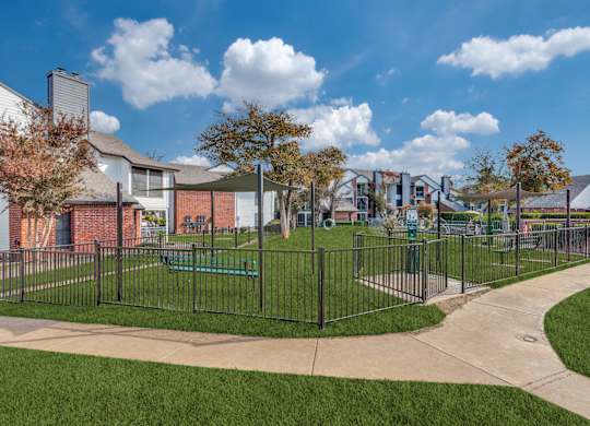 A park with a fence and a bench in front of a building.