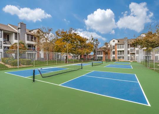 A tennis court surrounded by a fence and buildings.