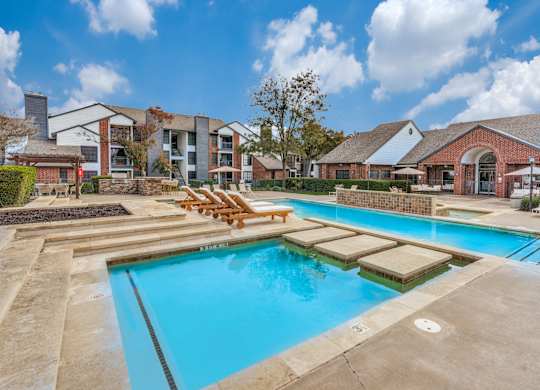 A large outdoor swimming pool with loungers and a building in the background.