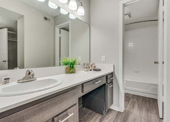 A bathroom with a white sink and a mirror above it.