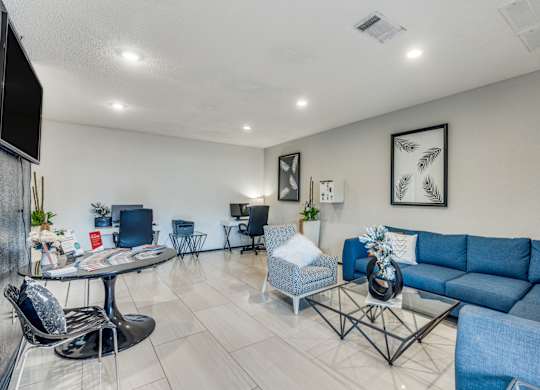 A living room with a blue couch and a glass table.