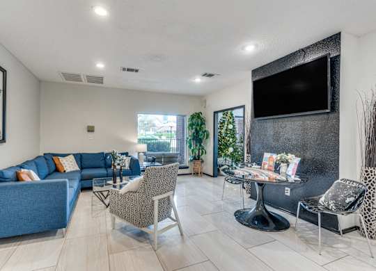 A living room with a blue couch and a television on the wall.
