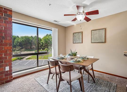 A dining room with a table set for two and a fan on the ceiling.