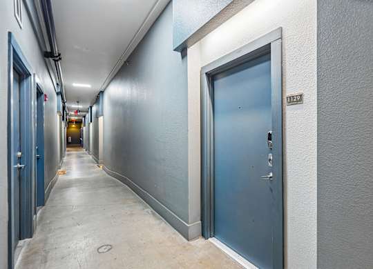 A long hallway with doors on both sides and a sign on the wall.