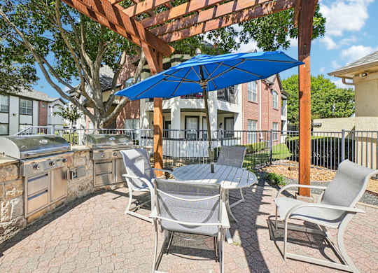 A patio with a table and chairs under a blue umbrella.